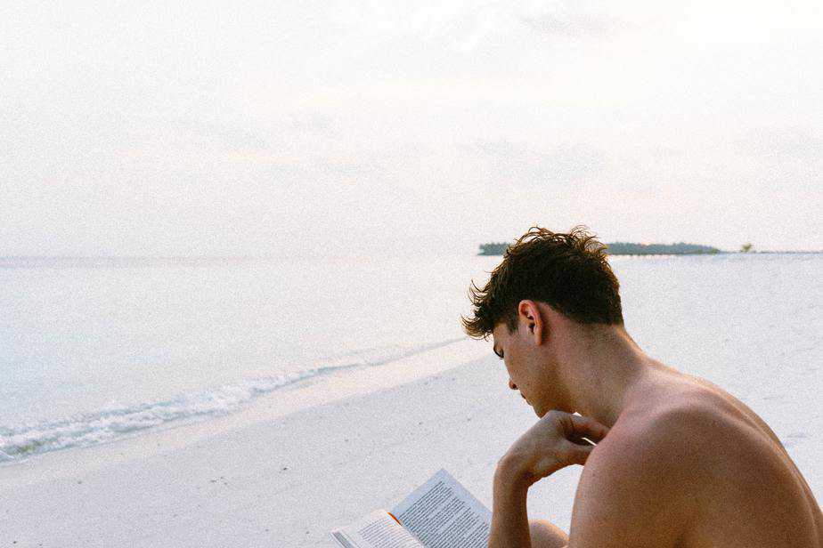 young-man-reading-book-alone-beach-shore