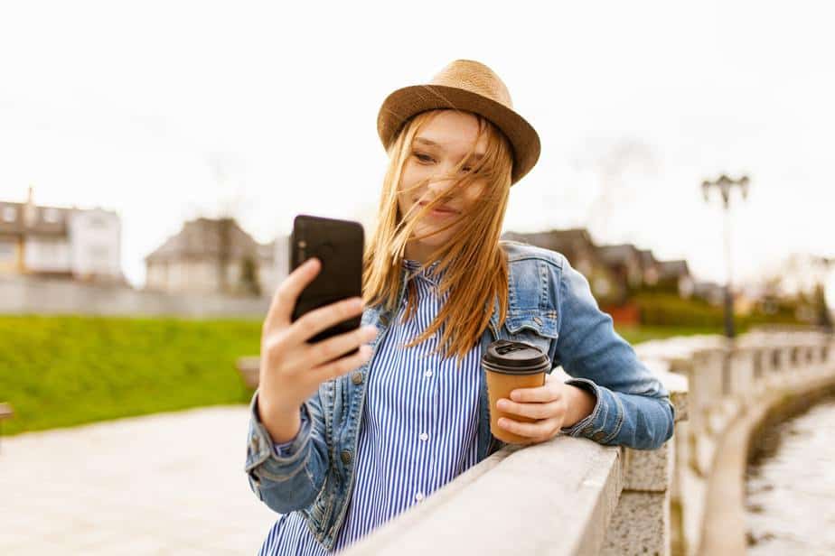 young-woman-wearing-hat-with-cellphone-and-coffee